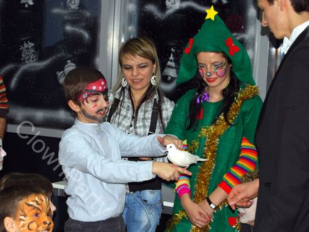 Magician petreceri copii făcând un truc cu un copil, la o petrecere de Crăciun