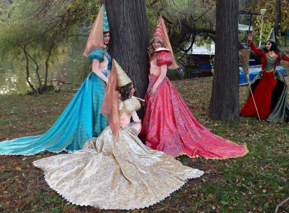 Ursitoare la botez în costume de lux, pe iarbă, într-o grădină